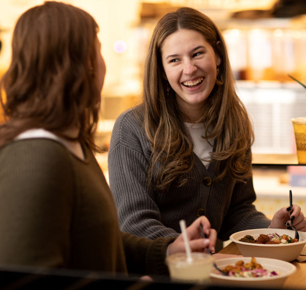 two friends each enjoying a taim bowl together in a taim restaurant