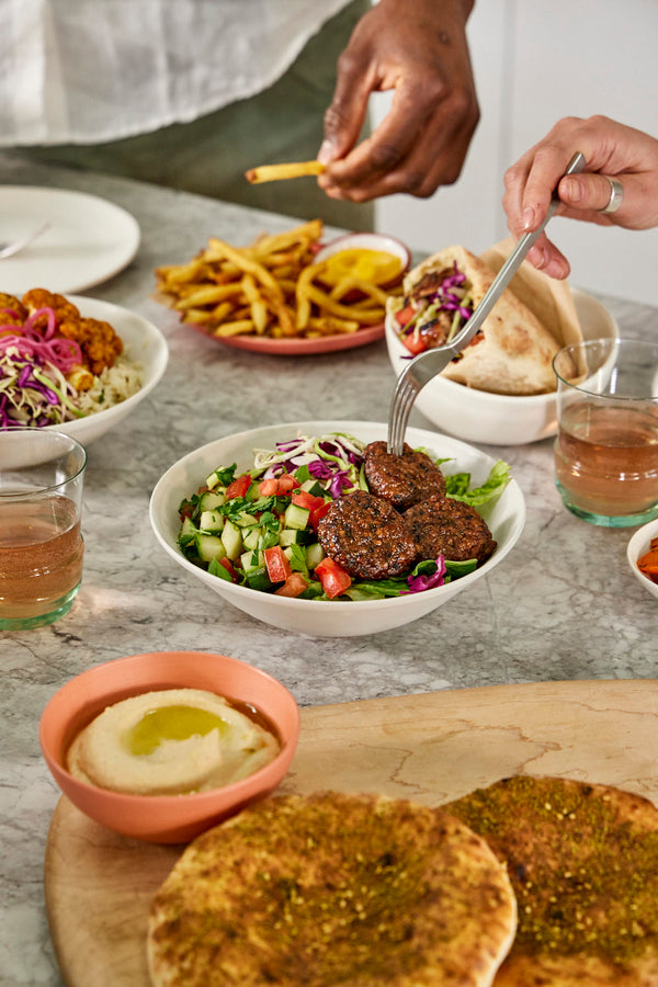 kitchen table filled with taim food and friends ready to dig in and enjoy. 